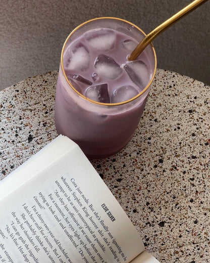 glass of purple matcha with a book 
